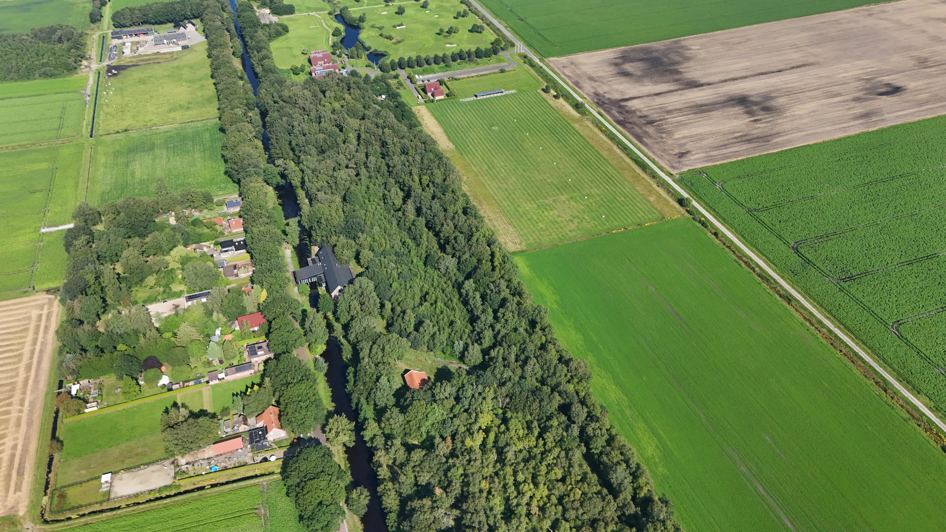 Cozmoss verscholen tussen bomen en velden in het groen van Drenthe, vanuit de lucht