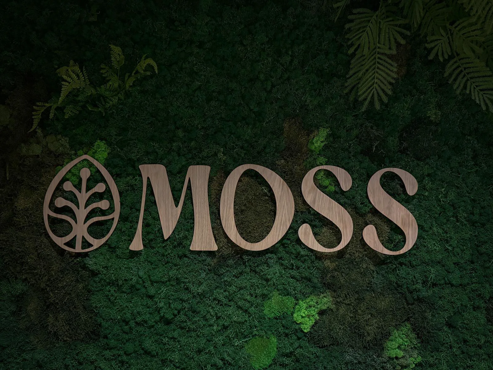 Het houten MOSS-logo op de donkergroene moswand, omlijst door varens