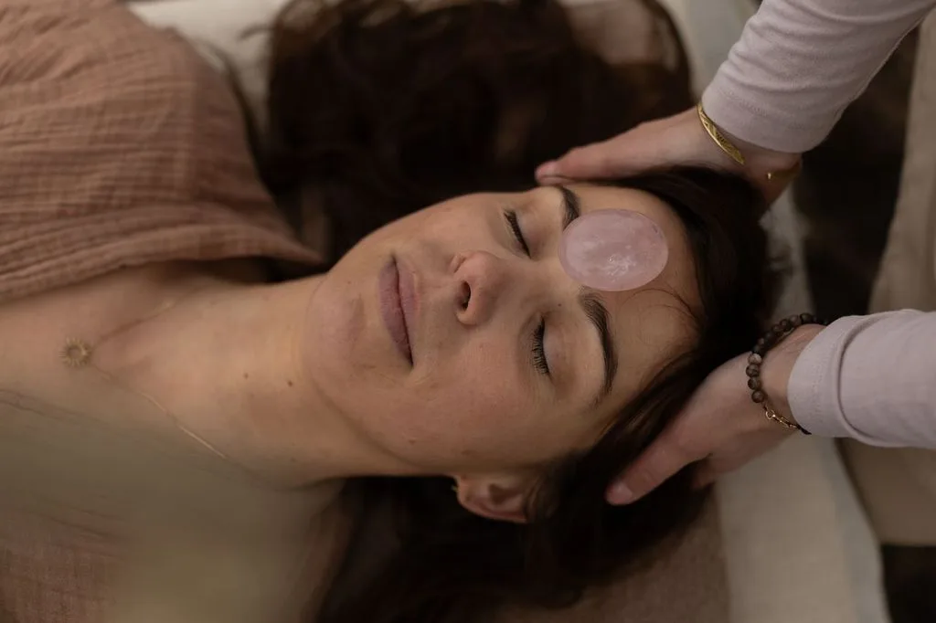 Holistische behandeling bij MOSS Wellness met een rozenkwarts op het voorhoofd