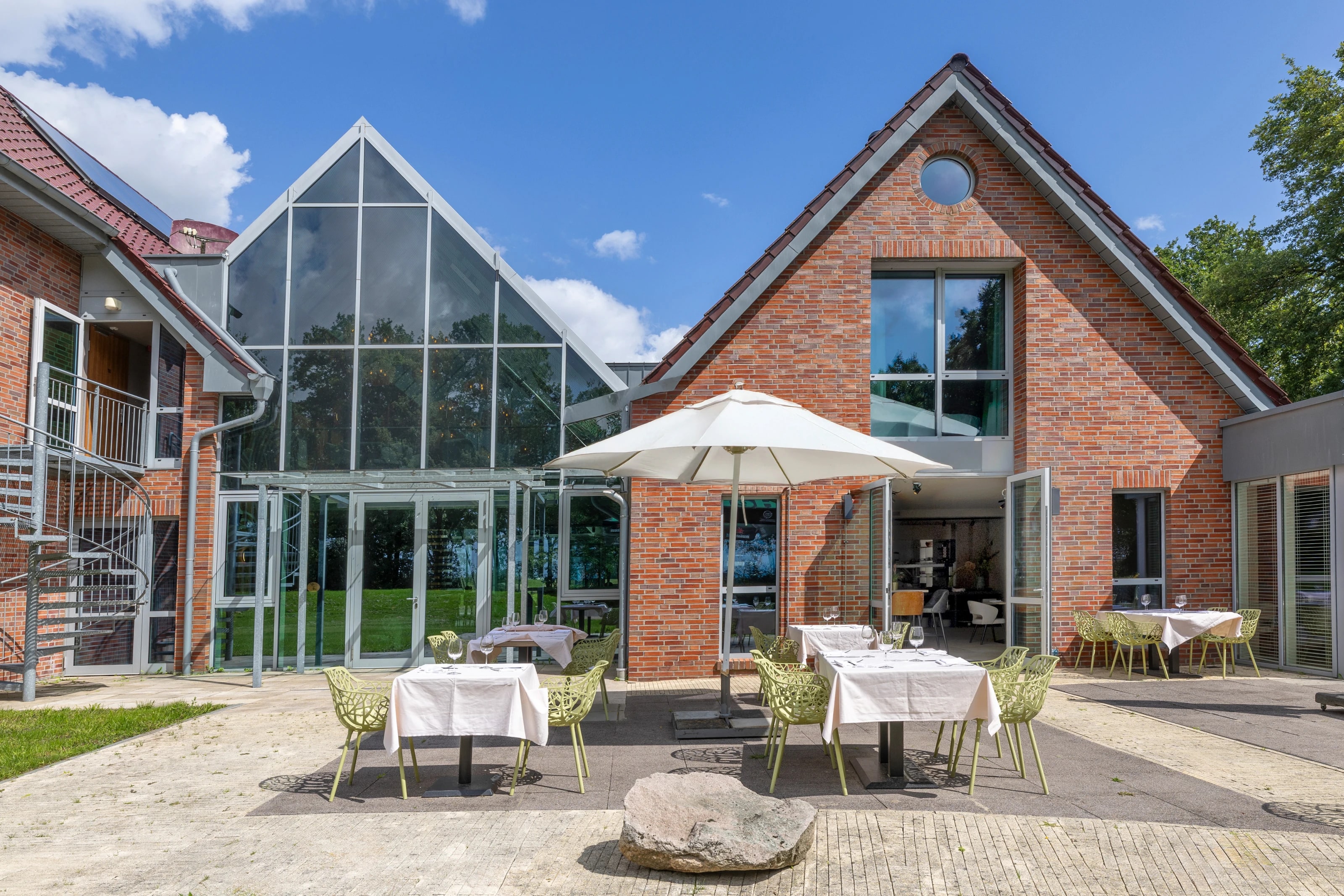 Het terras van Cozmoss met parasol en de glazen serre